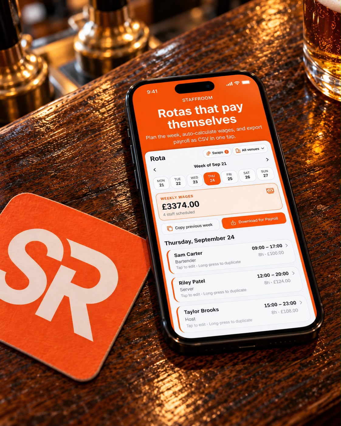 StaffRoom rota app on a phone resting on a pub bar beside a StaffRoom beer mat